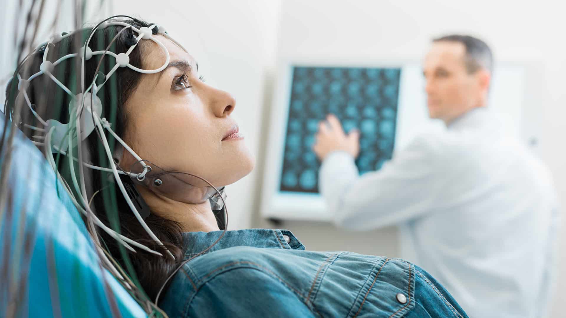 Ein Facharzt für Neurologie führt einen neurologischen Test mit Hilfe von Kopfsensoren durch.